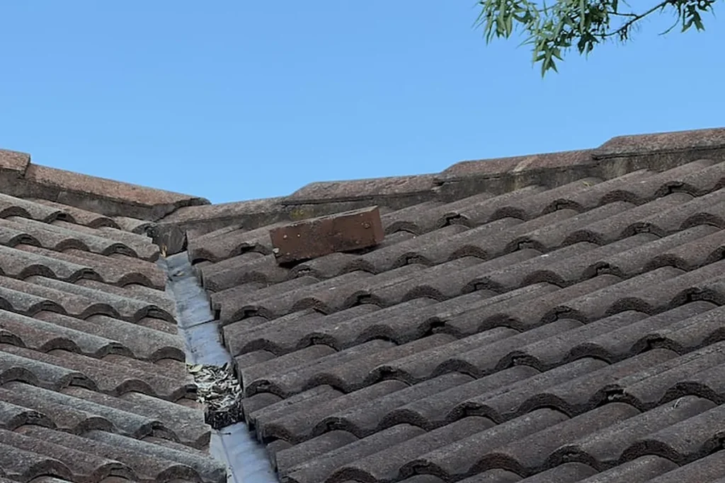 Weathered roof valley with a loose tile that needs repair