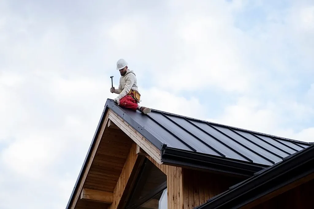 Roofer working on the ridge of a new metal roof installation