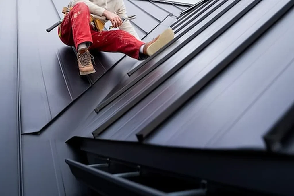 Roofer installing standing seam metal panels on a new roof
