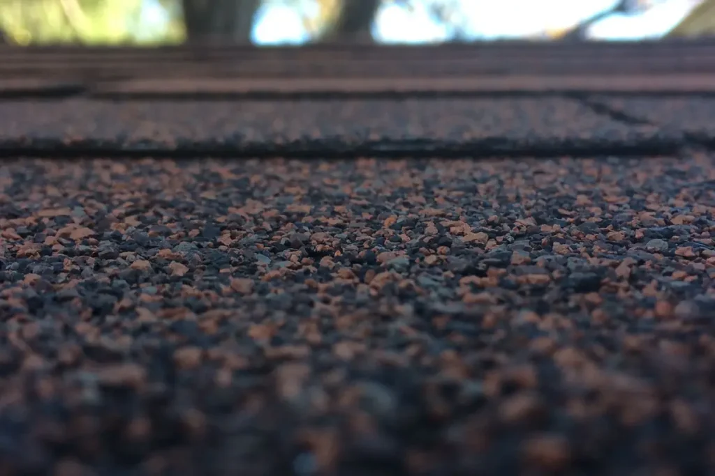 Close-up of worn asphalt roof shingles showing granule loss
